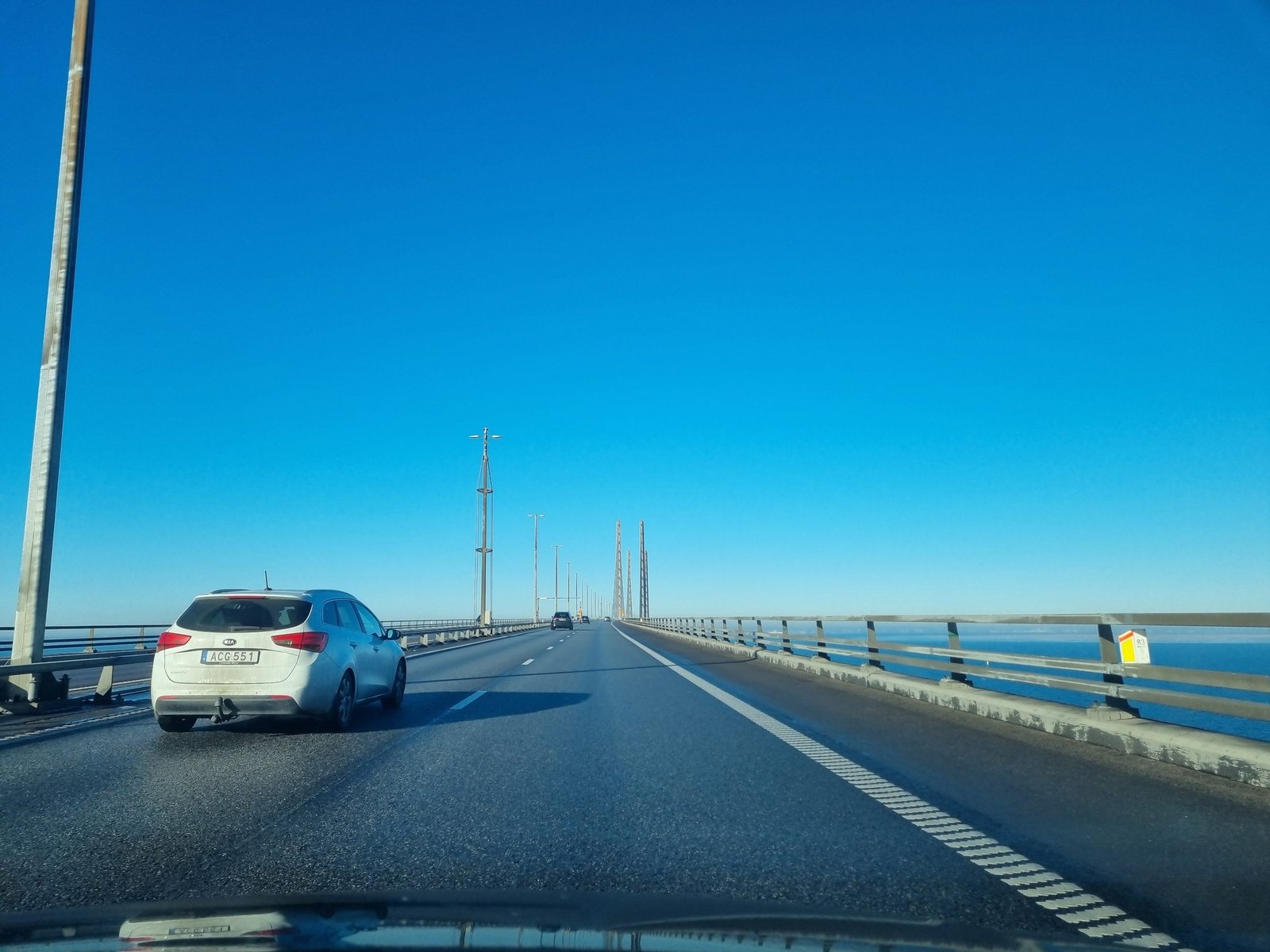 Bilkörning över Öresundsbron bakom en svensk personbil, med pylonerna i fjärran